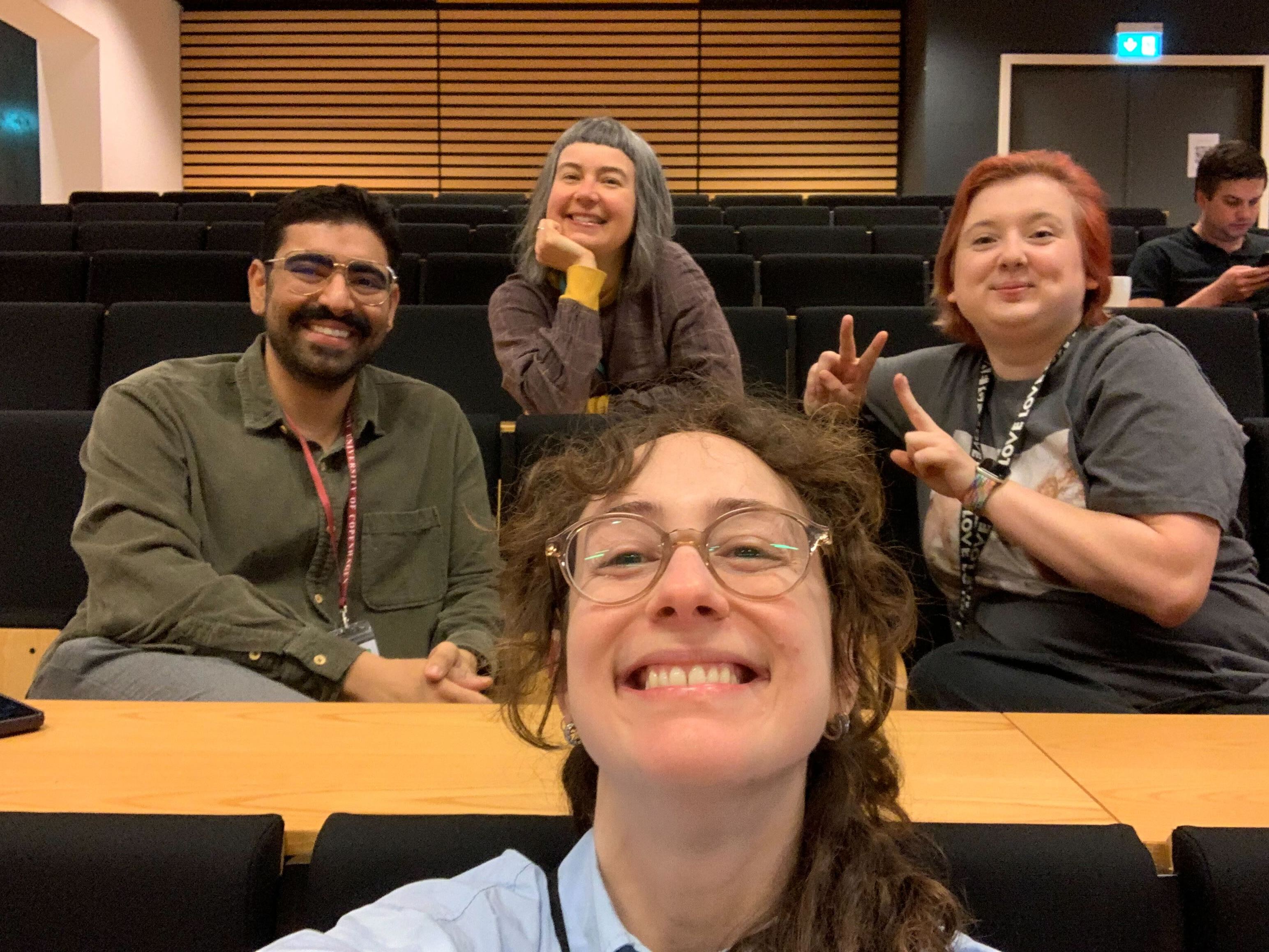 josé, miriah, kate, and derya smiling while sitting in a lecture hall
